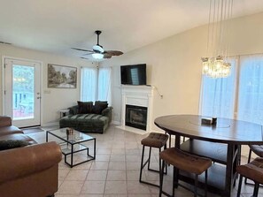 A living room with a fireplace, a television, a dining table, and a sofa. - Cozy 2-Bedroom Duplex in Little River (Little River)