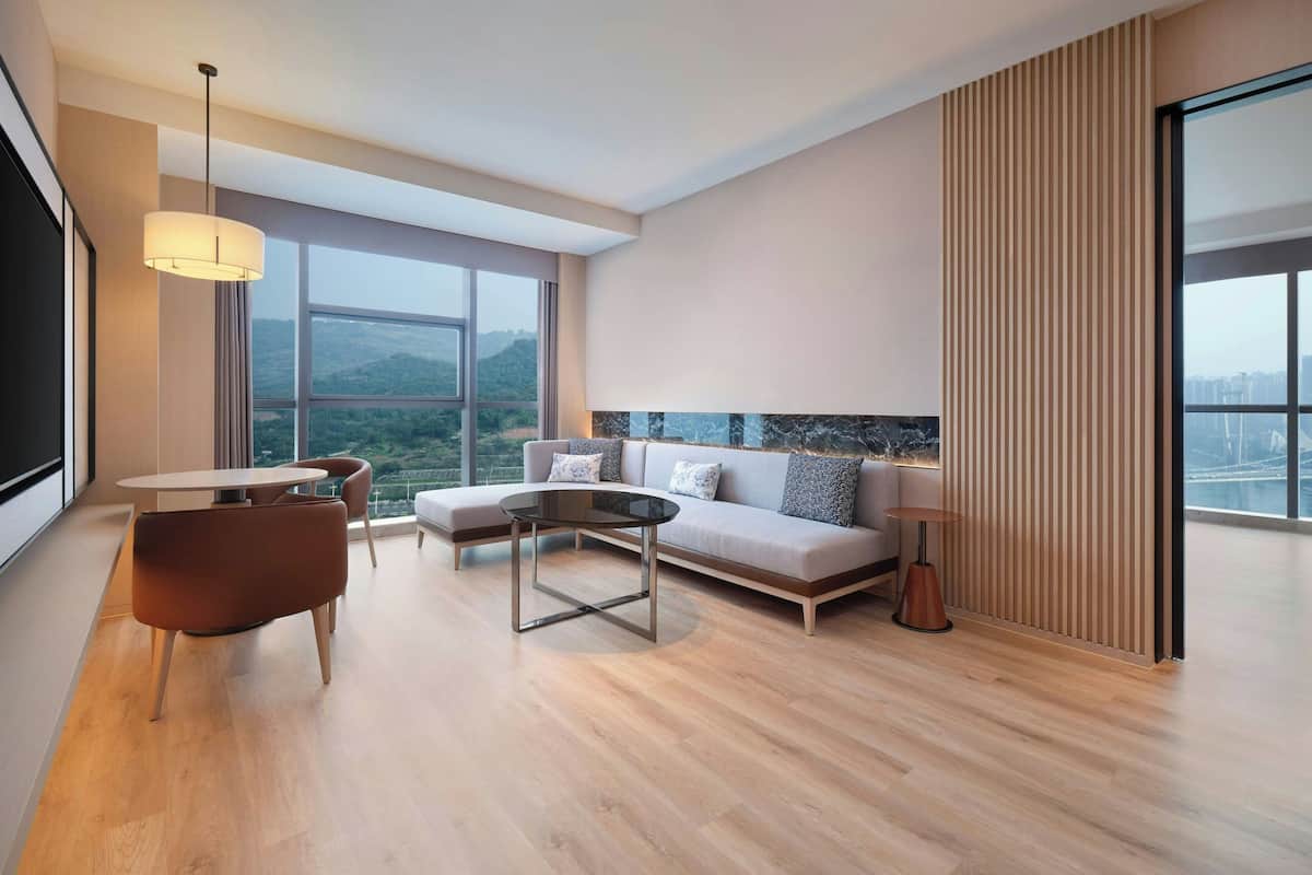 A modern living room with a sofa, a round coffee table, and a dining area with a table and chairs.