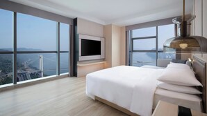 A modern hotel room with a large bed, a TV mounted on the wall, and a large window offering a view of a bridge and cityscape. - Courtyard By Marriott Chongqing Jiangjin (Chongqing)