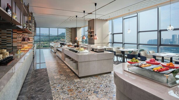 A modern hotel lobby with a central bar area, seating arrangements, and large windows offering a view of the cityscape. - Courtyard By Marriott Chongqing Jiangjin (Chongqing)