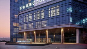 A modern hotel with a glass facade, titled "Courtyard by Marriott," featuring a spacious entrance and a prominent sign. - Courtyard By Marriott Chongqing Jiangjin (Chongqing)