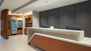 A reception area with a counter, a refrigerator stocked with beverages, and shelves with snacks. - Springhill Suites By Marriott Madison Fitchburg (Madison)