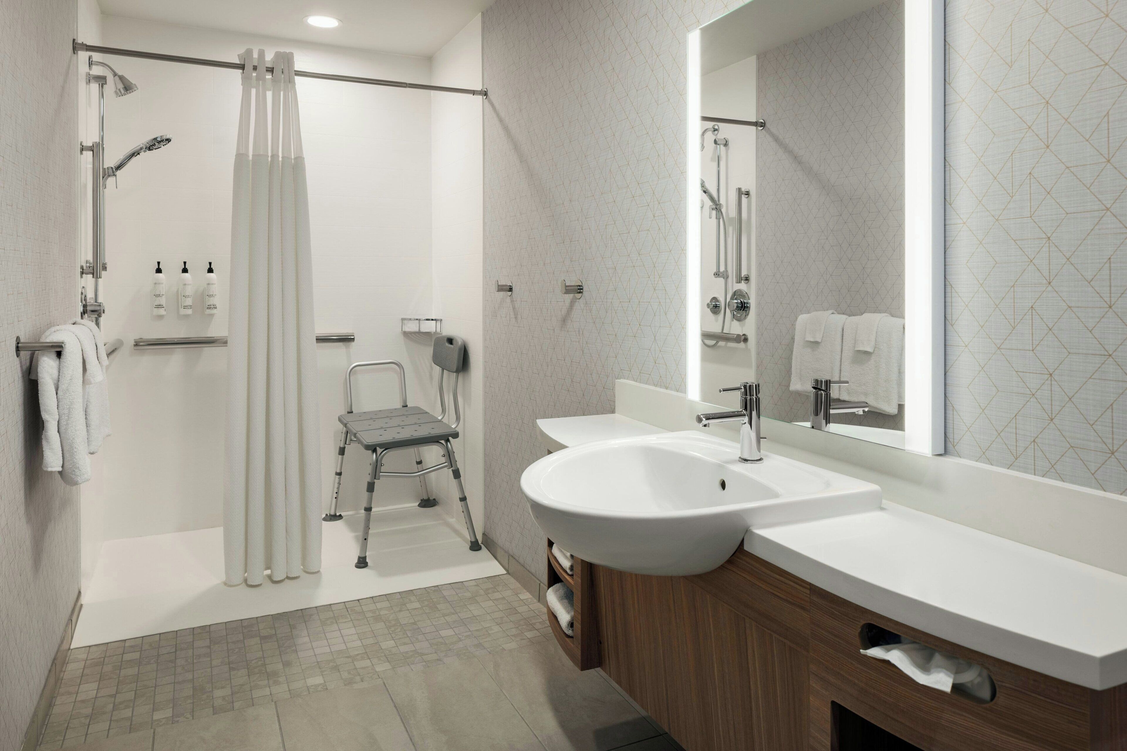 Une salle de bain moderne équipée d’une douche, de toilettes, d’un lavabo et d’un miroir.