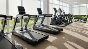 A row of treadmills in a well-lit indoor area with large windows. - Springhill Suites By Marriott Madison Fitchburg (Madison)