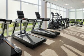 A row of treadmills in a well-lit indoor area with large windows. - Springhill Suites By Marriott Madison Fitchburg (Madison)