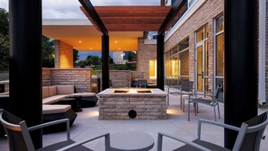 An outdoor patio with a stone fire table, seating, and a pergola. - Springhill Suites By Marriott Madison Fitchburg (Madison)