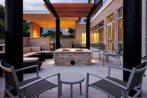 An outdoor patio with a stone fire table, seating, and a pergola. - Springhill Suites By Marriott Madison Fitchburg (Madison)