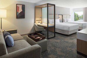 Ein Hotelzimmer mit Bett, Schreibtisch, Stuhl, kleinem Tisch und einem Fenster mit Blick.