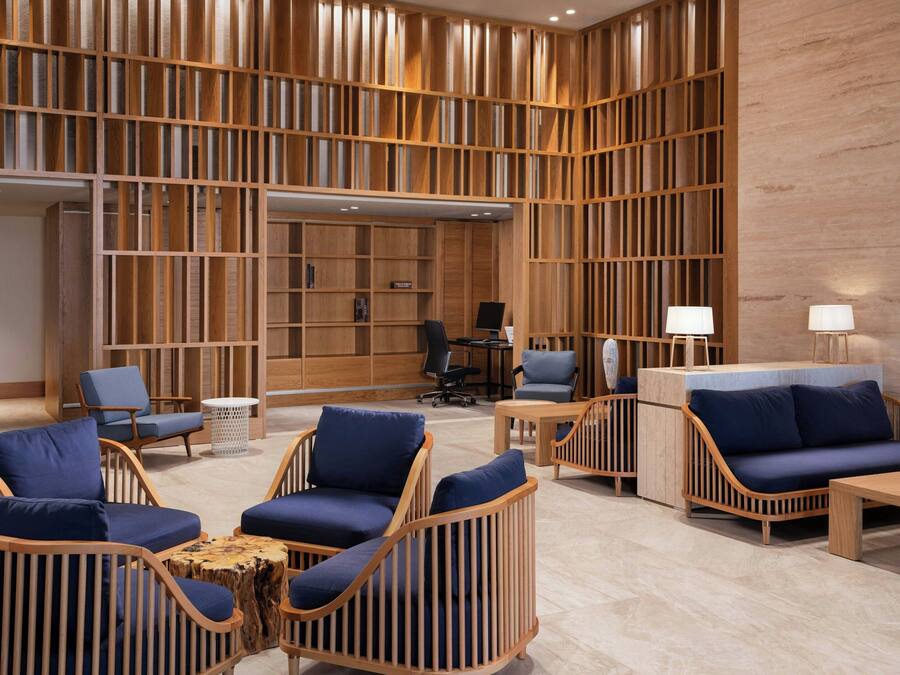 A modern lobby with wooden paneling, seating areas, and a reception desk.