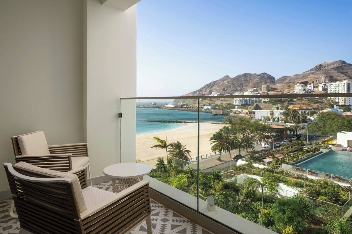 Un balcon avec vue sur une plage, une piscine et des montagnes.