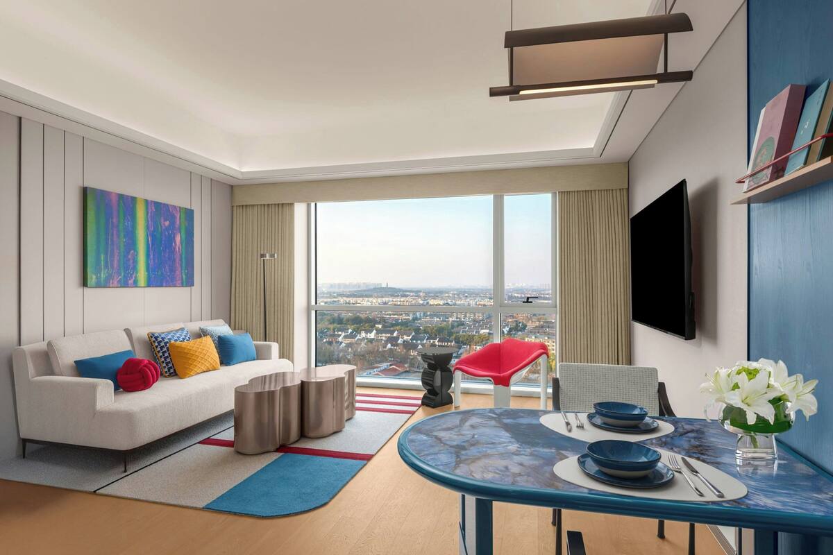 Una sala de estar moderna con un sofá, una mesa de comedor y un ventanal con vistas a la ciudad.