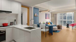 A modern kitchen with white cabinets, a built-in oven, and a red pot on the countertop. - Artik Suzhou, Apartments By Marriott Bonvoy (Suzhou)