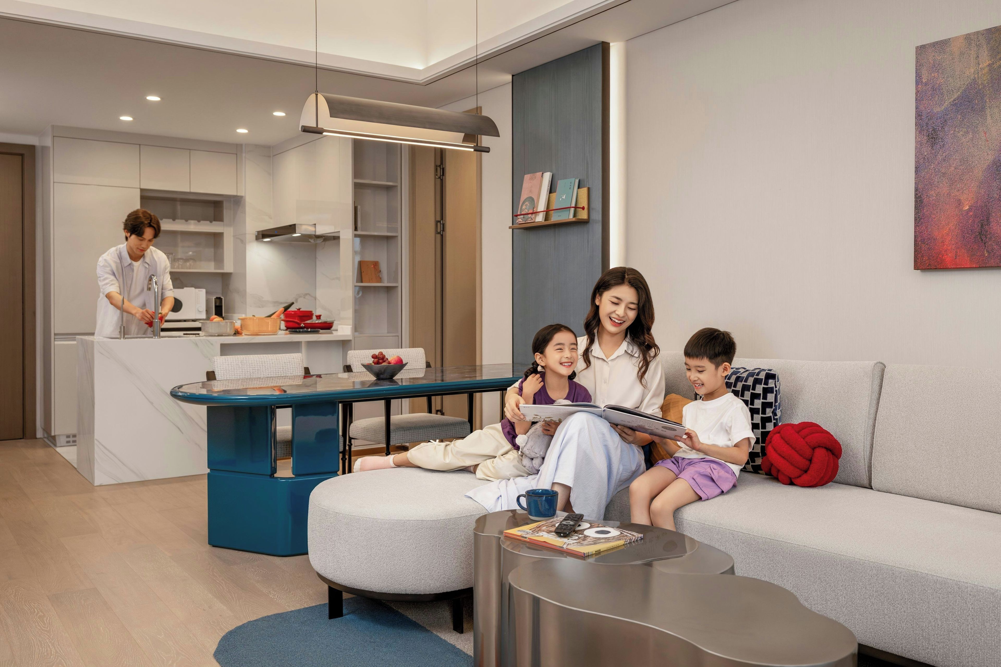 A modern living room with a sofa, a coffee table, and a dining area with a kitchen in the background.
