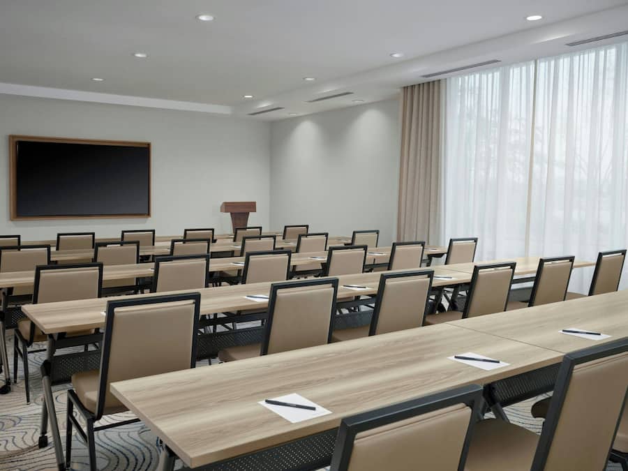 A conference room with multiple tables and chairs, a large blackboard, and a podium.