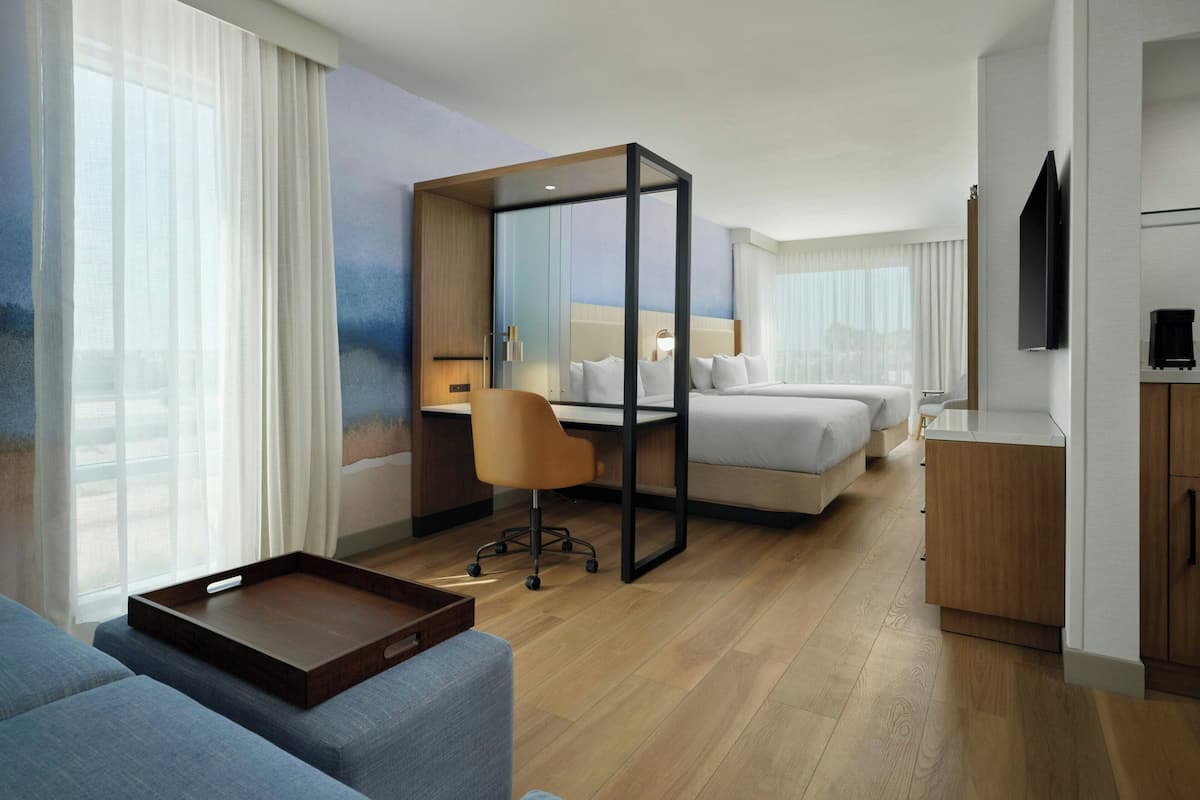 A hotel room with a bed, a desk, a chair, a TV, and a window with curtains.