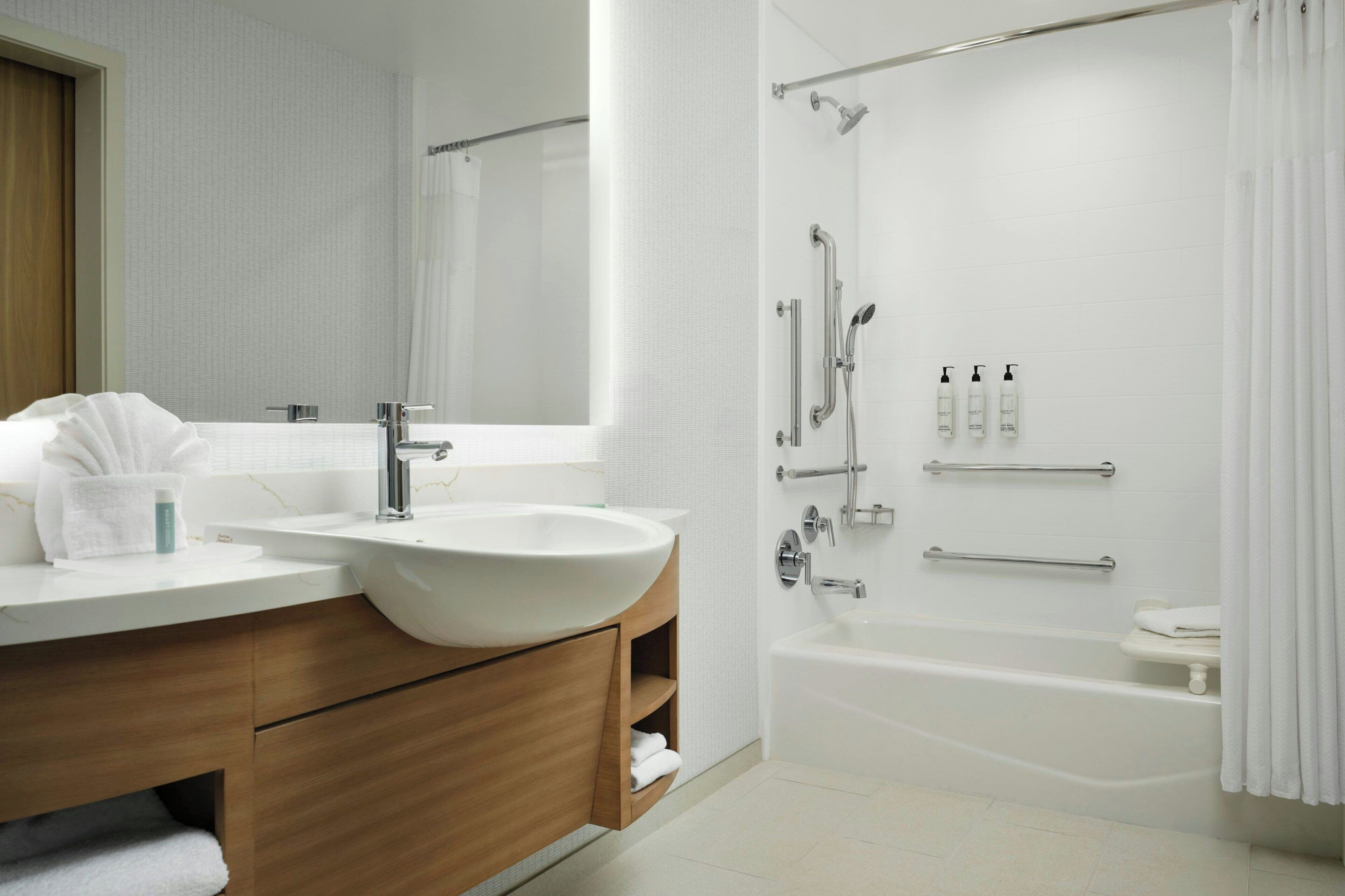 A modern bathroom with a large sink, mirror, shower, and bathtub.