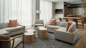 A modern living room with sofas, a coffee table, and a dining area with a table and chairs. - Springhill Suites By Marriott Ventura Oxnard (Oxnard)