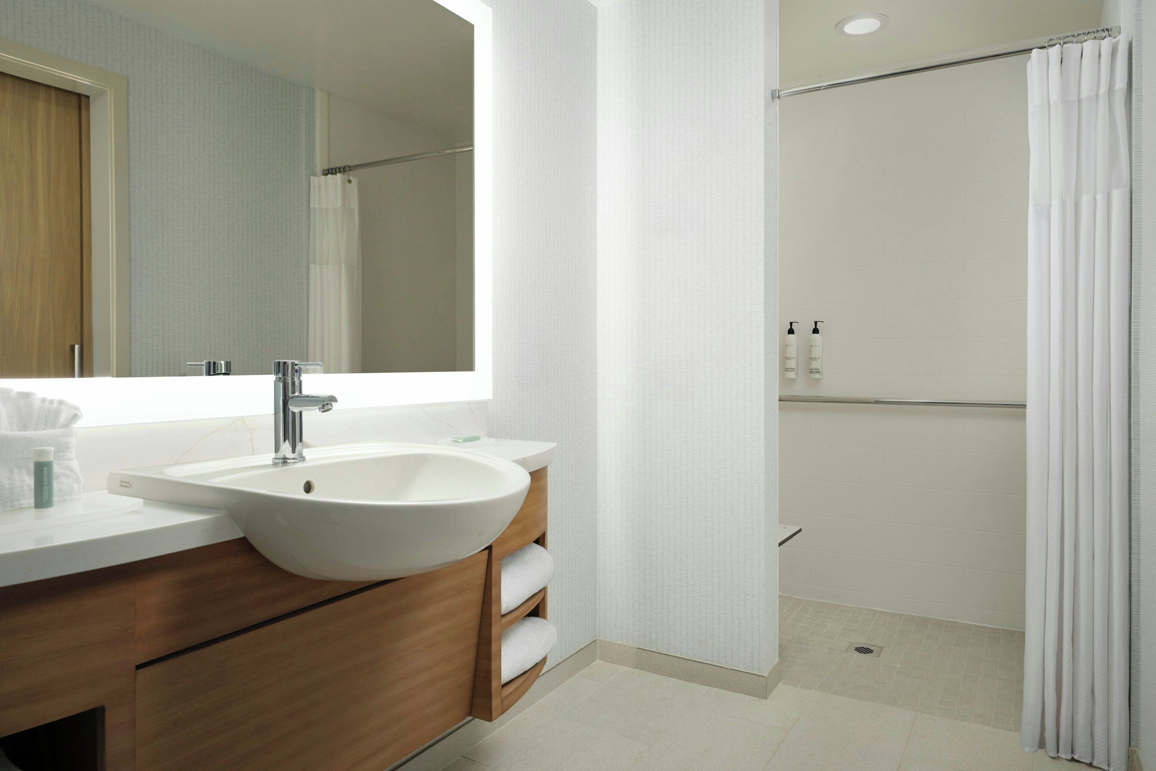 A modern bathroom with a large sink, mirror, and shower curtain.