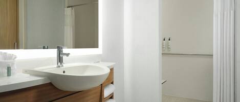 A modern bathroom with a large sink, mirror, and shower curtain.