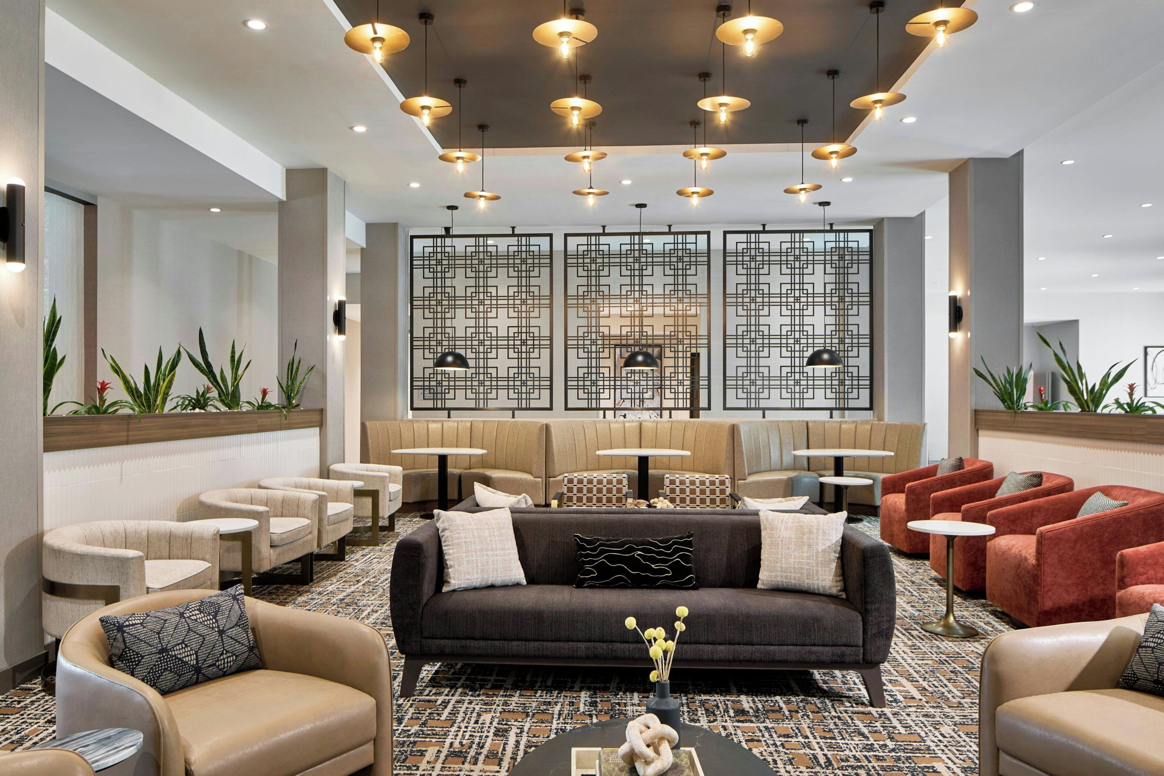 A modern lobby with a sofa, armchairs, and a seating area with tables.