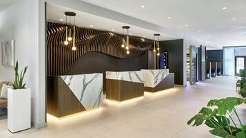 Un comptoir d’accueil moderne, doté d’un plateau en marbre et de panneaux en bois, agrémenté de luminaires suspendus.