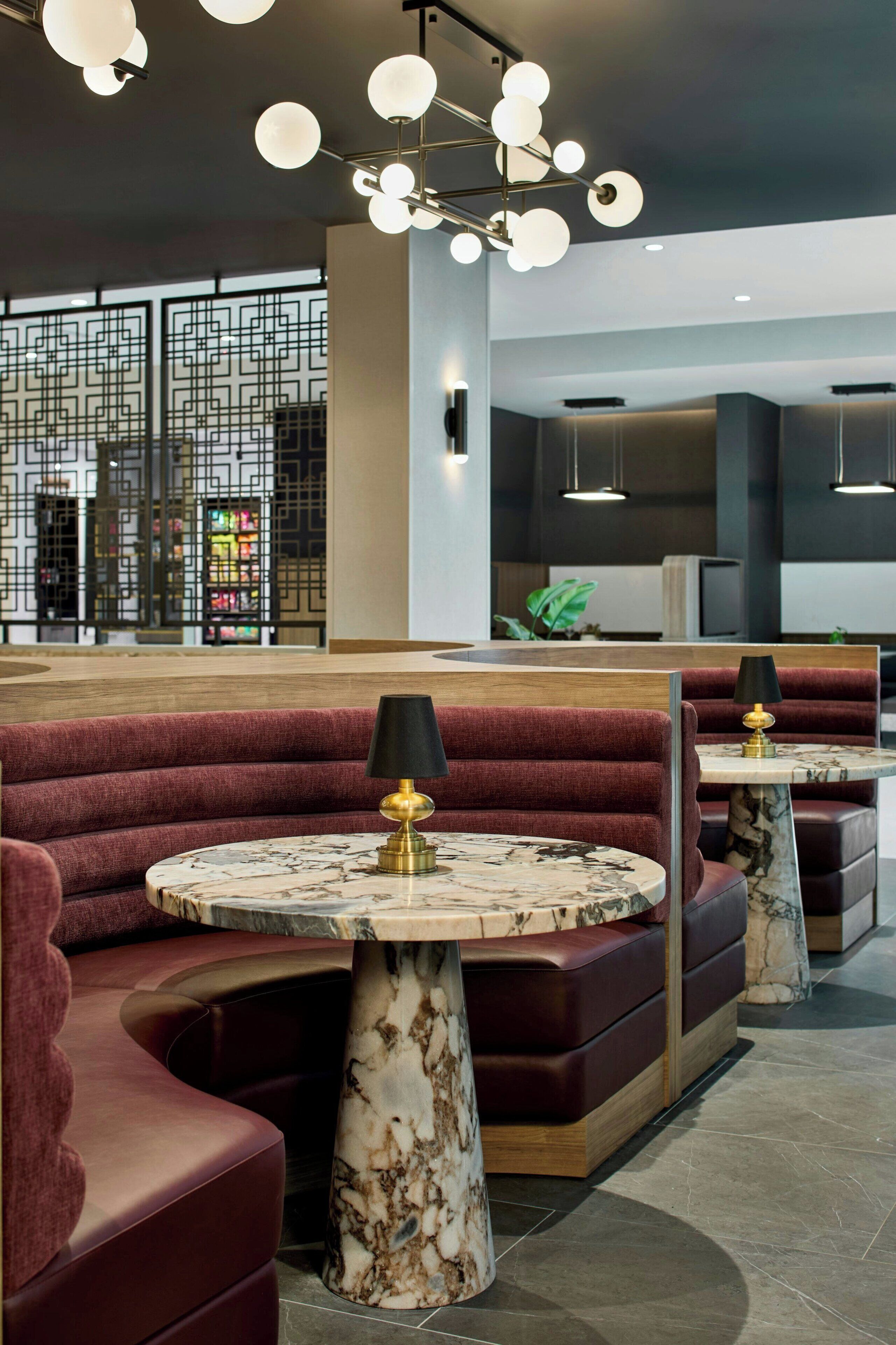 A modern interior with seating areas, marble-topped tables, and a decorative ceiling light fixture.