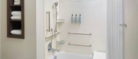 A bathroom with a bathtub, shower, towel rack, and toiletries.