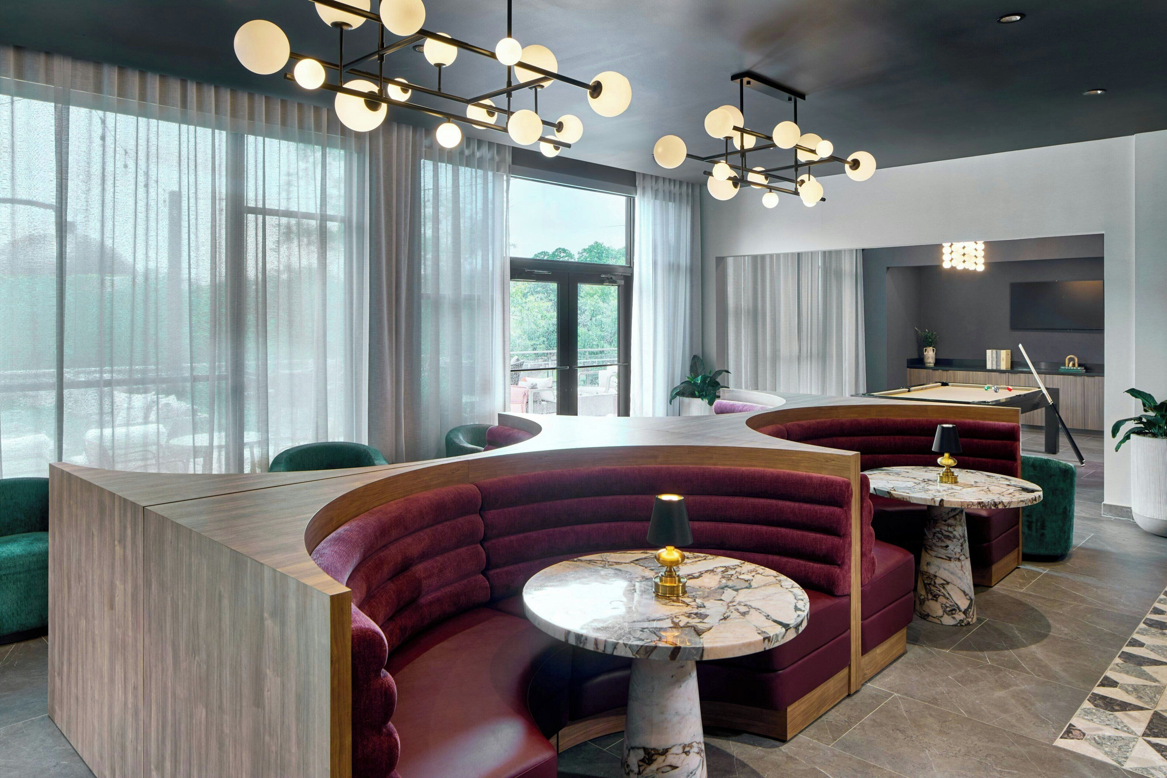 Un interior moderno con asientos curvos, una mesa de billar y una zona de bar.