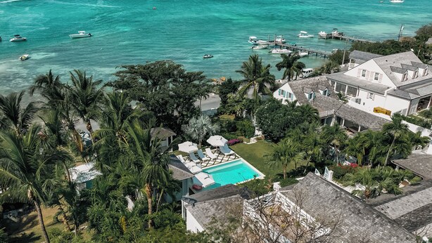 Una propiedad costera con piscina, palmeras y un muelle con barcos.