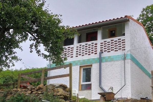 Ein zweistöckiges Gebäude mit Balkon, Steinmauer und Holzzaun.