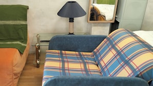 Una habitación con cama, sofá, lámpara y una pequeña mesa.