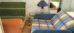 A room with a bed, a sofa, a lamp, and a small table.