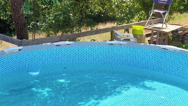 Una piscina al aire libre con cubierta de madera y una silla.