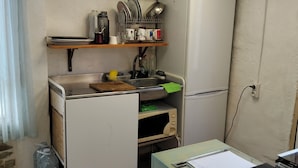 Cocina compacta con lavamanos, microondas y una pequeña encimera.