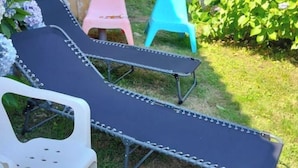 Un jardin avec une table de billard, un fauteuil et une petite table.