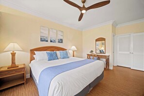 A neatly arranged bedroom with a bed, two bedside tables with lamps, a wooden headboard, a ceiling fan, and a wardrobe. - Beachfront Ocean View Oasis w/Saltwater Pool (Kapaʻa)