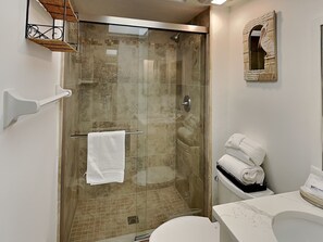 A modern bathroom with a glass-enclosed shower, a white toilet, and a sink with a mirror above it. - Carlos Pointe 422 (Fort Myers Beach)