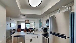 Cozinha moderna com ilha planejada, eletrodomésticos de aço inoxidável e área de refeições com vista.
