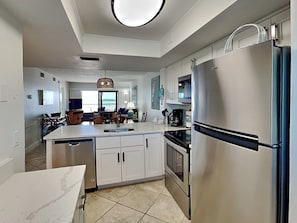 Een moderne keuken met een inbouw eiland, roestvrijstalen apparatuur en een eethoek met uitzicht.