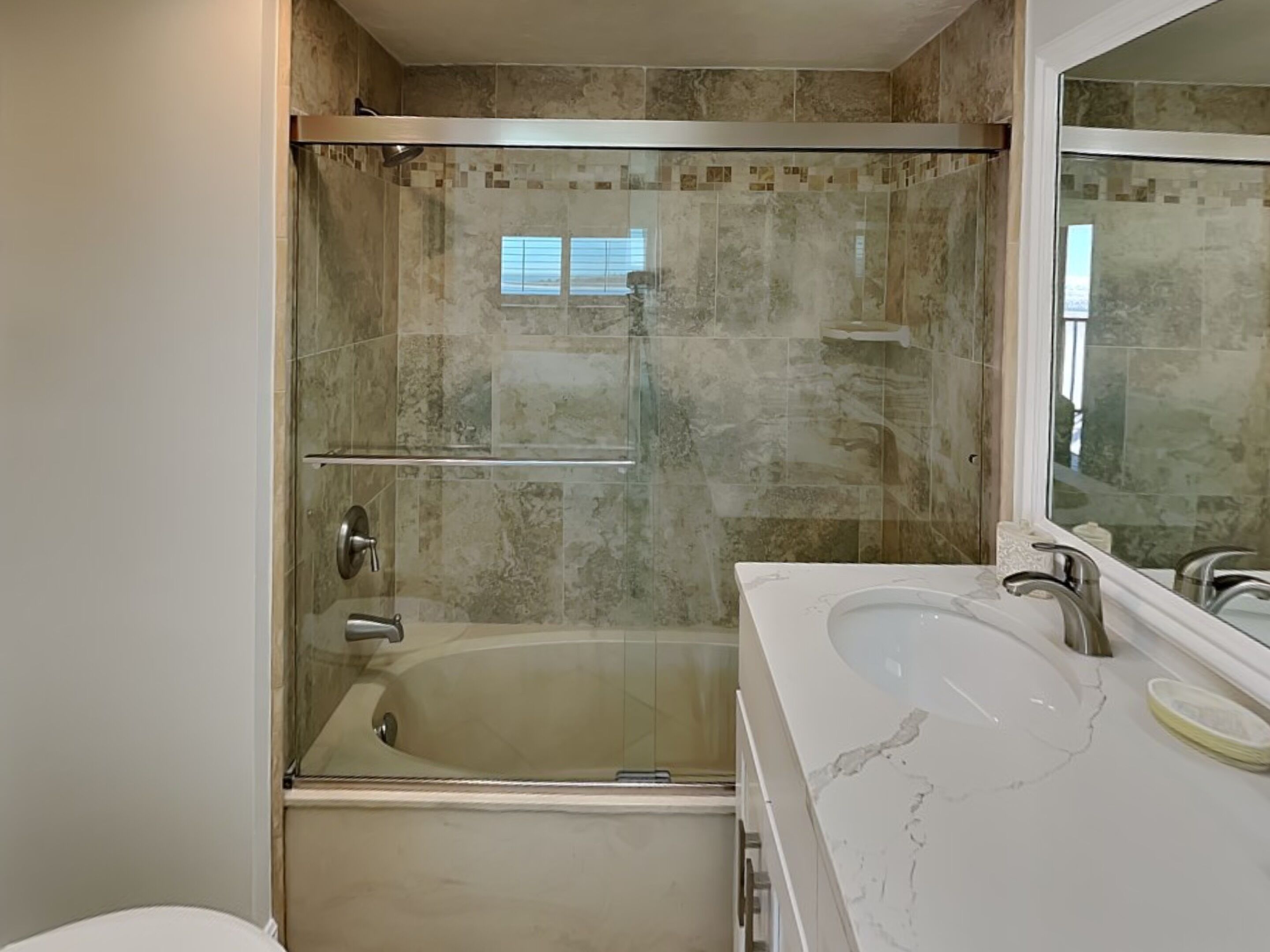 A modern bathroom with a glass-enclosed shower, a bathtub, and a large mirror.