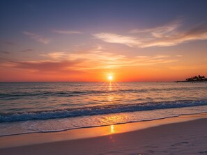 Une plage où le soleil se couche sur l’océan, créant une atmosphère paisible et sereine.
