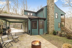 Ein Haus mit einem Steinkamin, einer überdachten Terrasse und einer Feuerstelle.