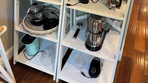 Een keuken met witte planken met diverse keukenapparaten en spullen.