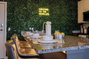 A modern kitchen with a green wall and a neon sign that reads "WELCOME TO THE GOOD LIFE." - 2-King Beds apartment in Richmond w/ 80' projector, AC and fitness room (Richmond)