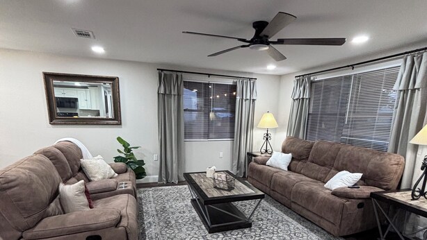A modern living room with two brown sofas, a patterned rug, a coffee table, and a ceiling fan. -  The Happy Place, a Charming & Cozy 3-bedroom home in the heart of Sneads, FL. (Sneads)