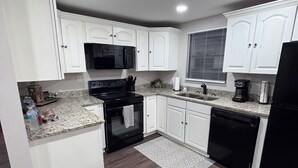 A modern kitchen with white cabinetry, a black stove, a microwave, and a dishwasher. -  The Happy Place, a Charming & Cozy 3-bedroom home in the heart of Sneads, FL. (Sneads)