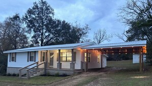 A single-story house with a covered porch and a small staircase leading to the entrance. -  The Happy Place, a Charming & Cozy 3-bedroom home in the heart of Sneads, FL. (Sneads)