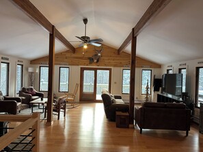 A spacious living room with wooden floors, a ceiling fan, and a television. - Cozy 3-Bedroom Mountain Style Home (Reading)