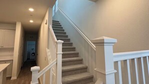 Una escalera con barandillas blancas y peldaños alfombrados que conduce a un cuarto de lavandería.