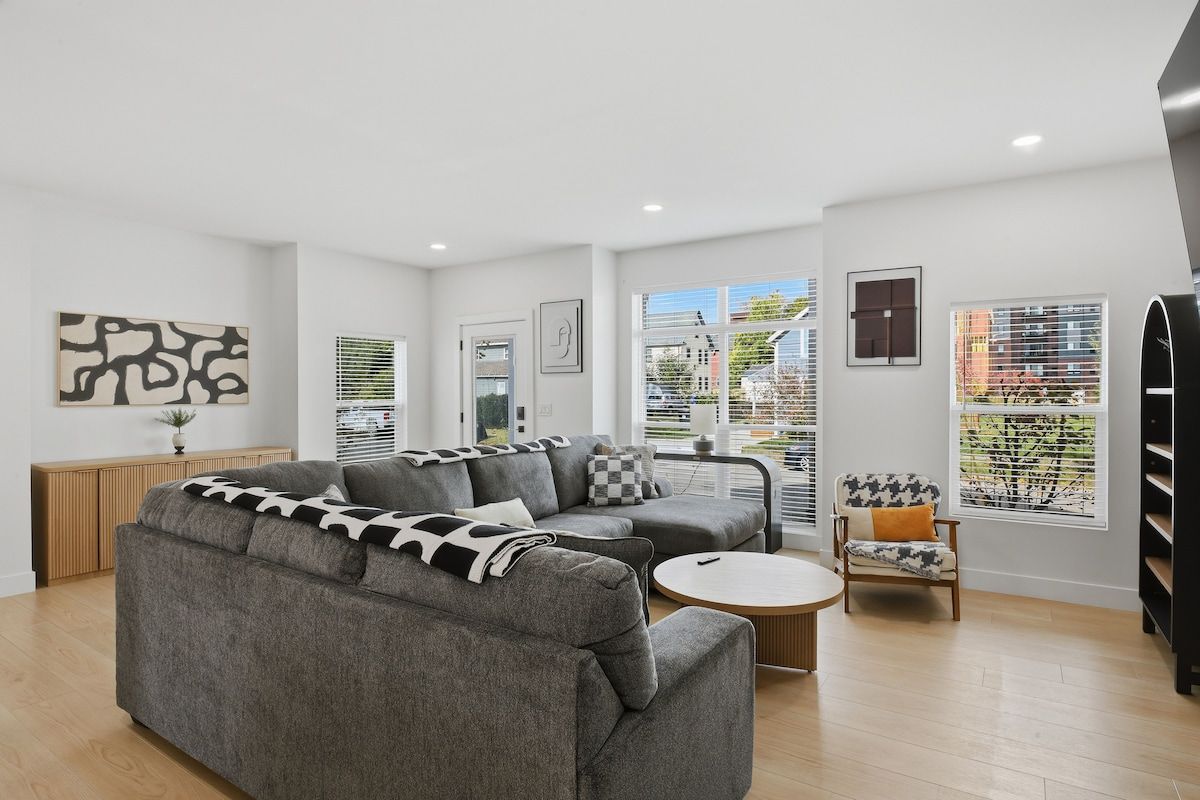 A modern living room with a sectional sofa, a round coffee table, and a patterned armchair.